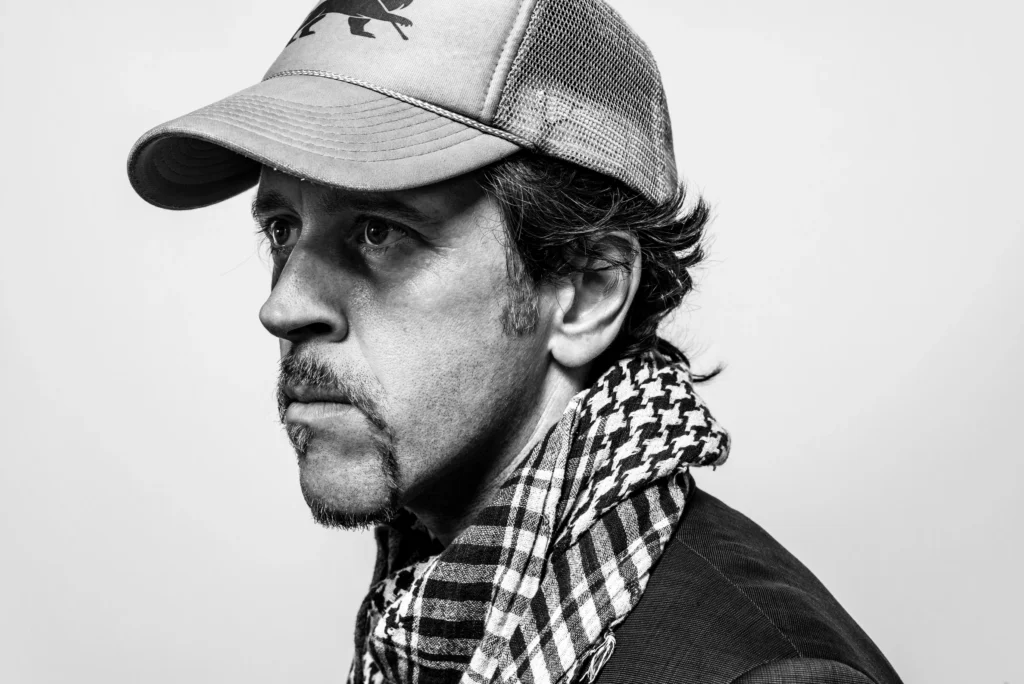 Black-and-white portrait of London DJ, remixer and producer Jstar wearing a cap and scarf, representing his work across Reggae, Dub, Dancehall and Hip Hop.