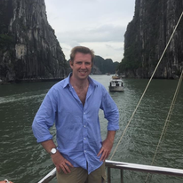 Freelance Journalist Thomas Simms standing on the back of a boat in Thailand.