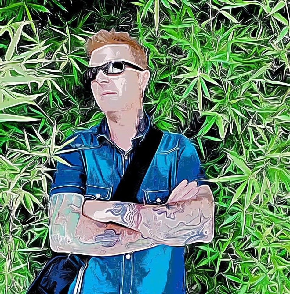 Stylised artwork of El Brujo wearing sunglasses and a blue shirt with folded arms, surrounded by dense green leaves.