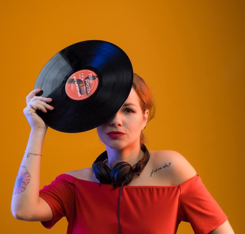 Russian DJ Foxy Tail standing and holding a vinyl record over her right eye, colour image for Scientific Sound Asia.