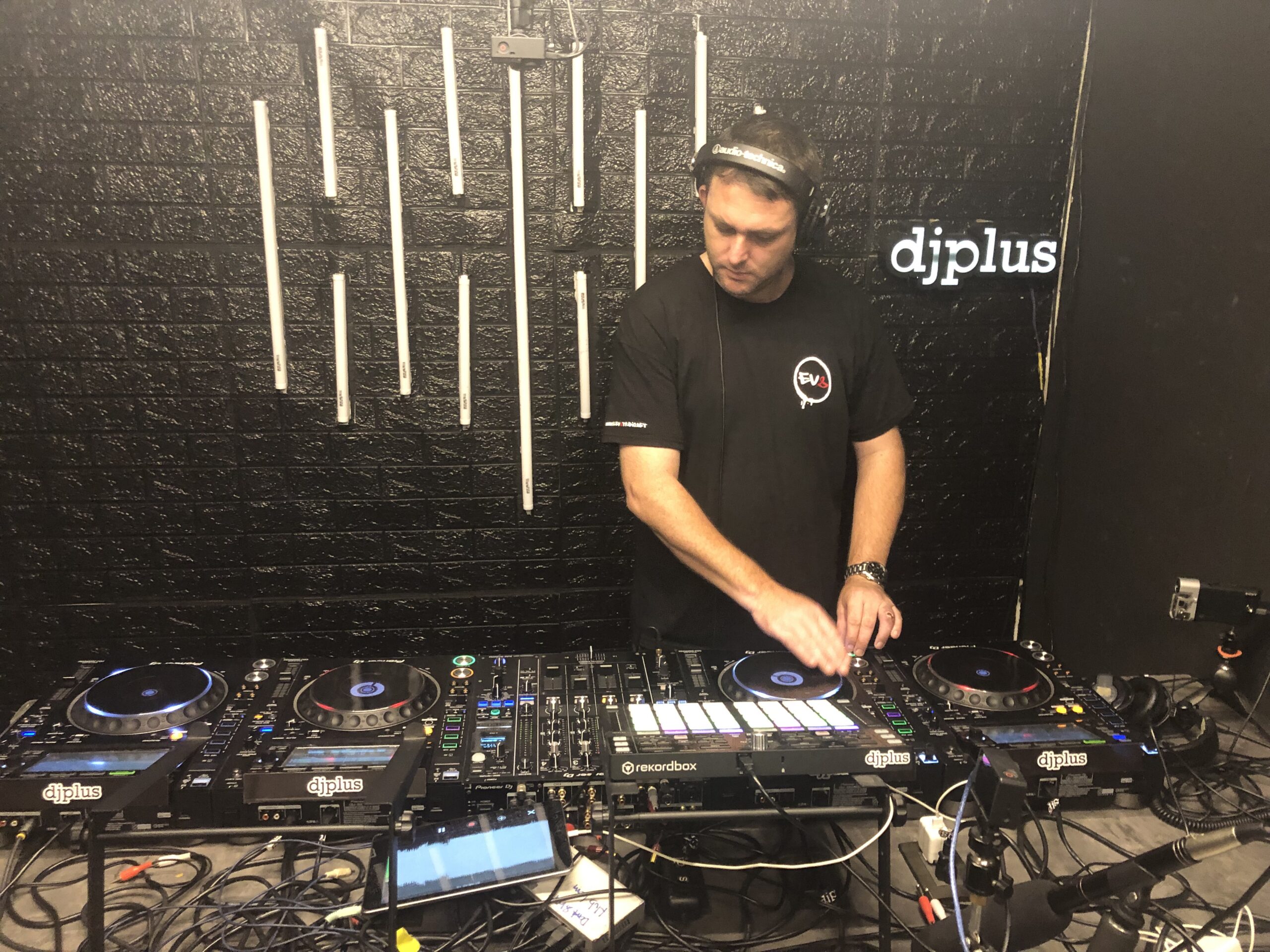 Mista C, London-born drum and bass DJ, performing on a four-deck Pioneer setup at DJ Plus studio.