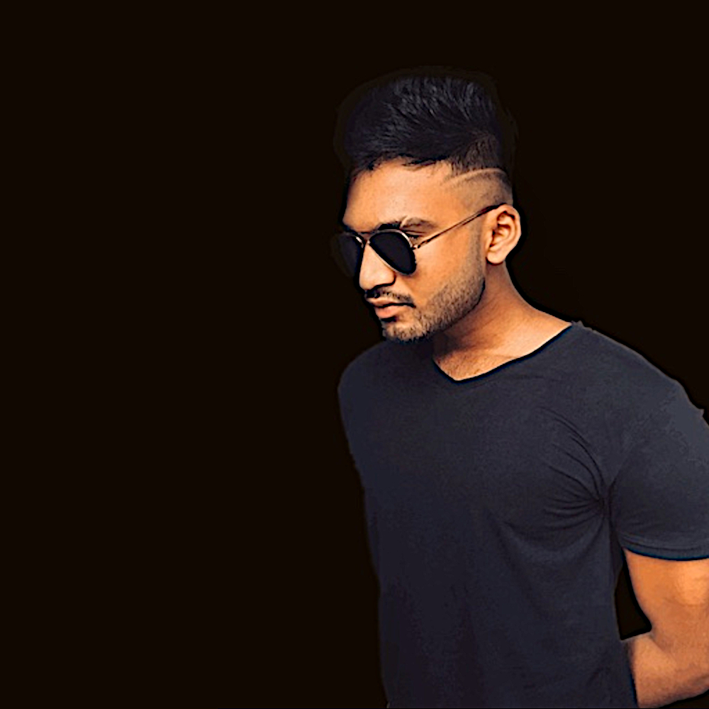 Sri lankan DJ and Producer Hersiaz Hazi standing wearing sunglasses looking right, colour image.