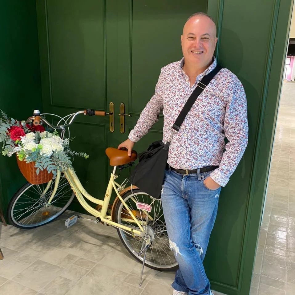 Italian DJ and producer Marco Mei leaning on a bicycle with his right hand, colour image.
