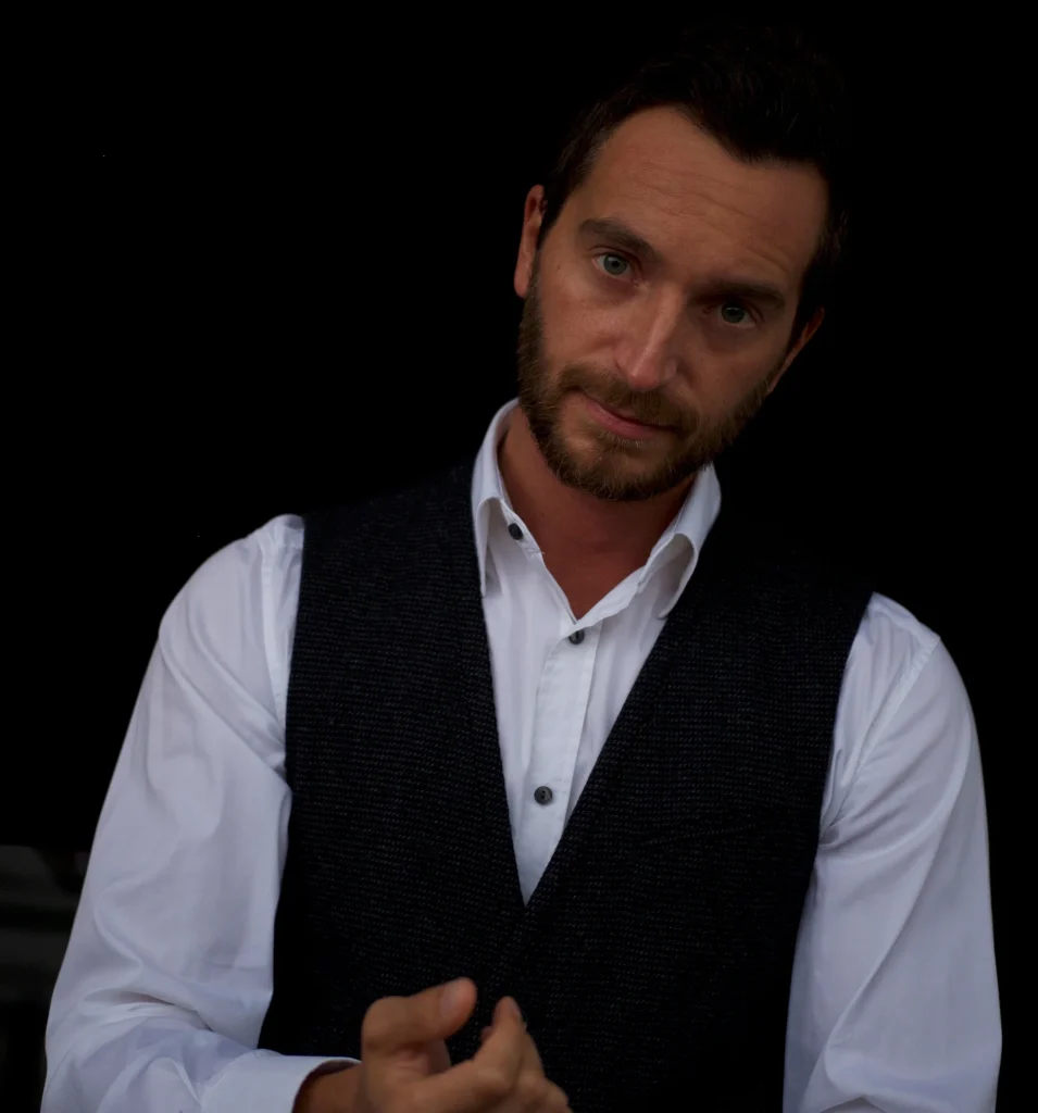 Italian DJ and Producer Inve standing in upper body shot wearing a shirt and waistcoat, colour image.