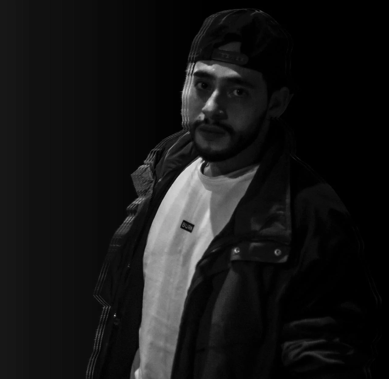 Colombian DJ and Producer Juan Vera in upper body shot looking at camera, black and white image.