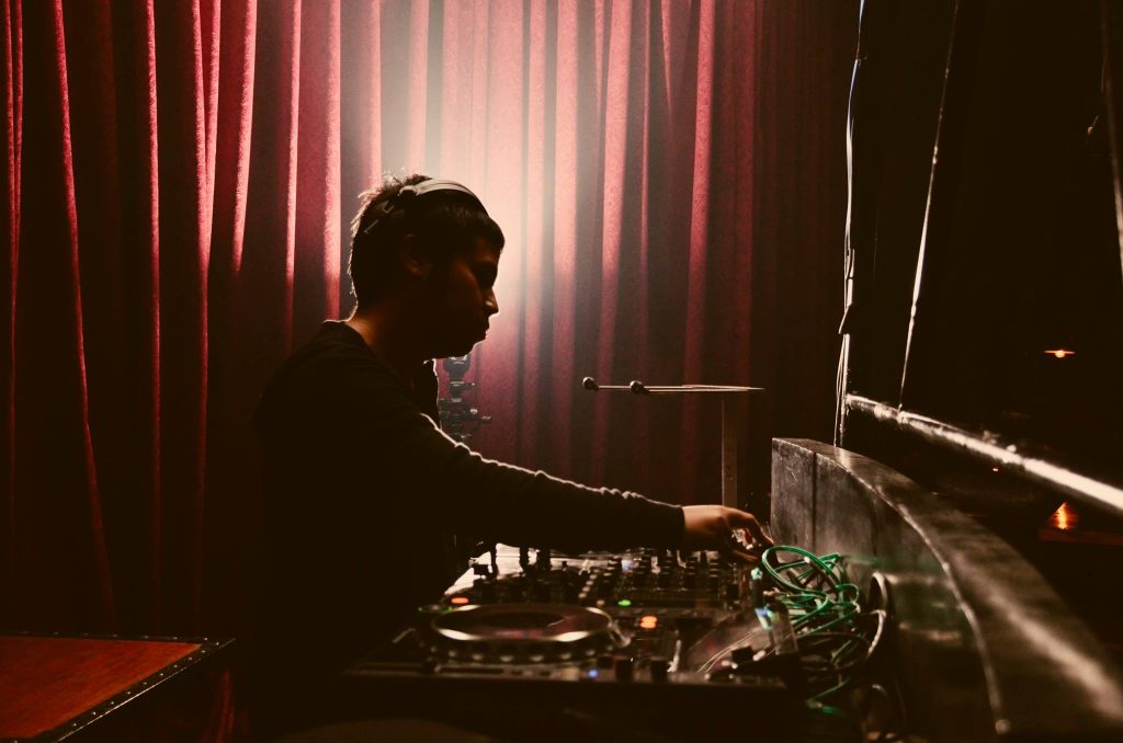 Indonesian DJ and producer Nandi performing at event, side image in colour.