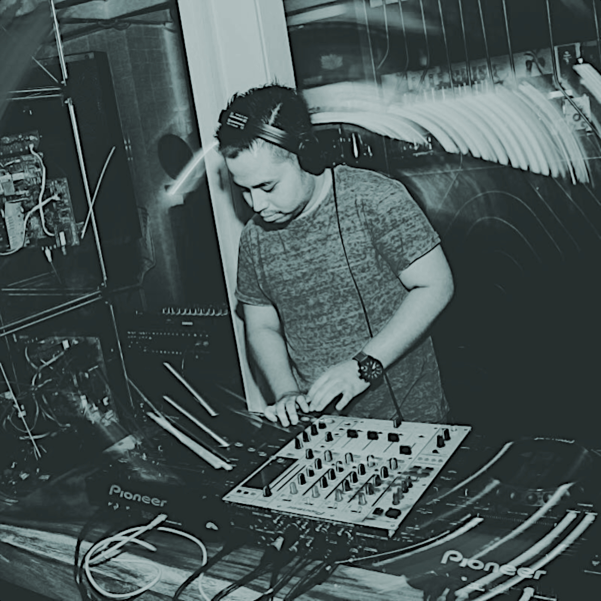 Indonesian DJ and producer Nandi performing on Pioneer CDJs at an event, black and white image with blue tinge.