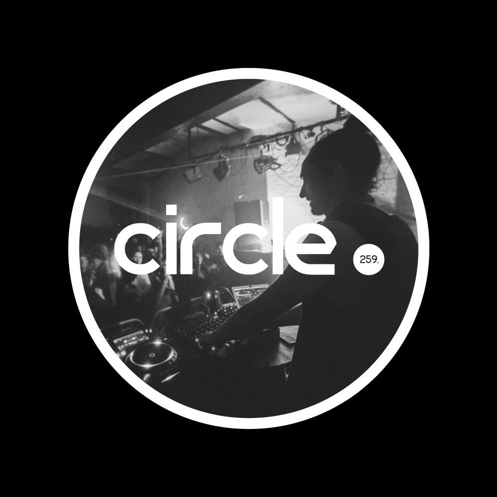 Pete Bidwell performing as a DJ behind circle. 259 logo in Black and white.