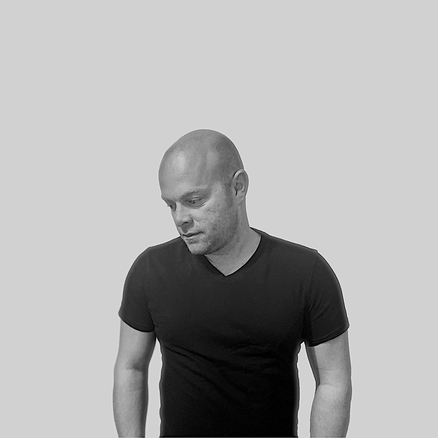 American DJ and producer Orticaan standing looking down in upper body shot, black and white image.