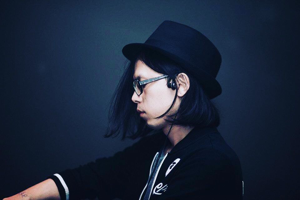 Taiwanese DJ and producer KJ Stone in side profile picture whilst performing wearing a hat and glasses, colour image.
