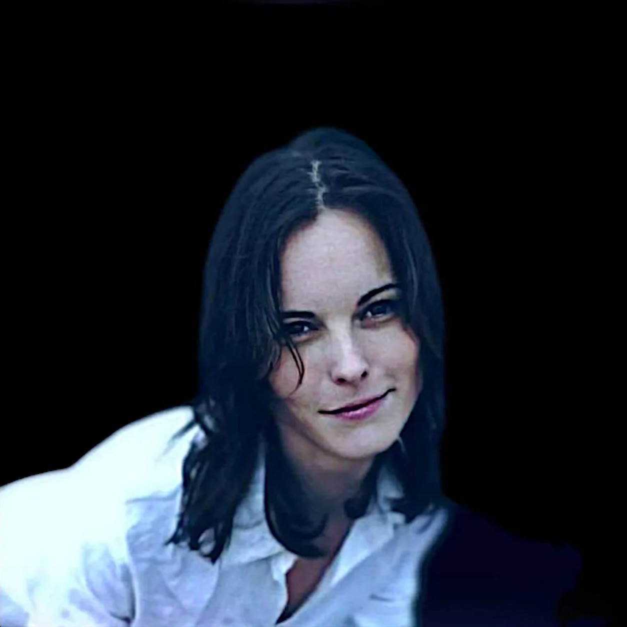 Hungarian DJ and producer Black Pearl smiling at camera in upper boday shot against black background, colour image.