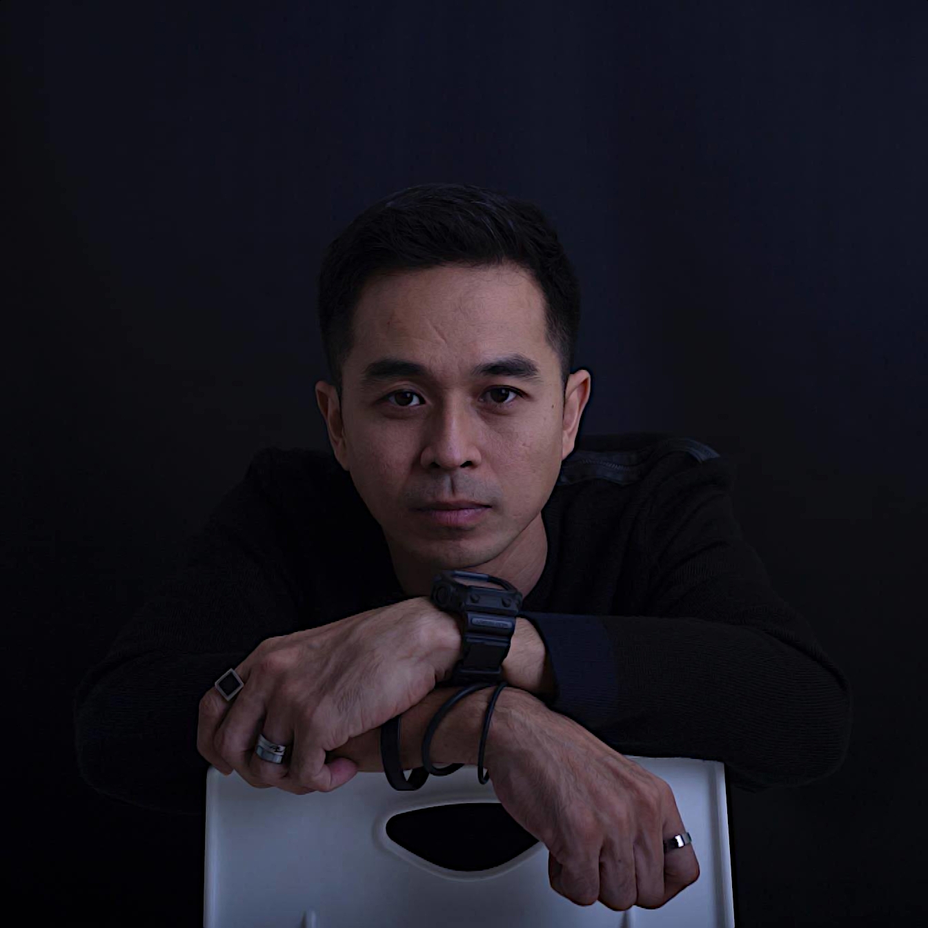 Malaysian DJ and producer Hadiid sitting backwwards on a chair with his arms on the backrest, colour image.