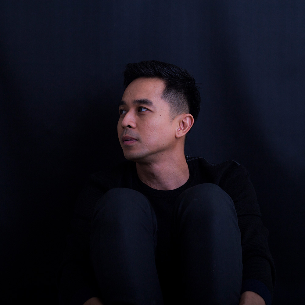 Malaysian DJ and producer Hadiid standing and looking up to his right, colour image.