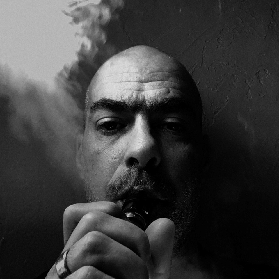 French DJ and producer Akira smoking a vape in a head shot, black and white image.
