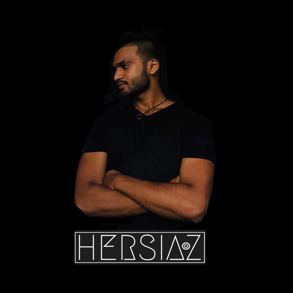 Sri lankan DJ and promoter Hersiaz Hazi standing looking right, colour image.