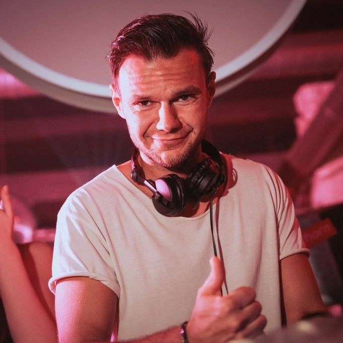 Italian DJ and Producer Andrea Mirgone standing looking at cameraman whilst smiling at an event, colour image.