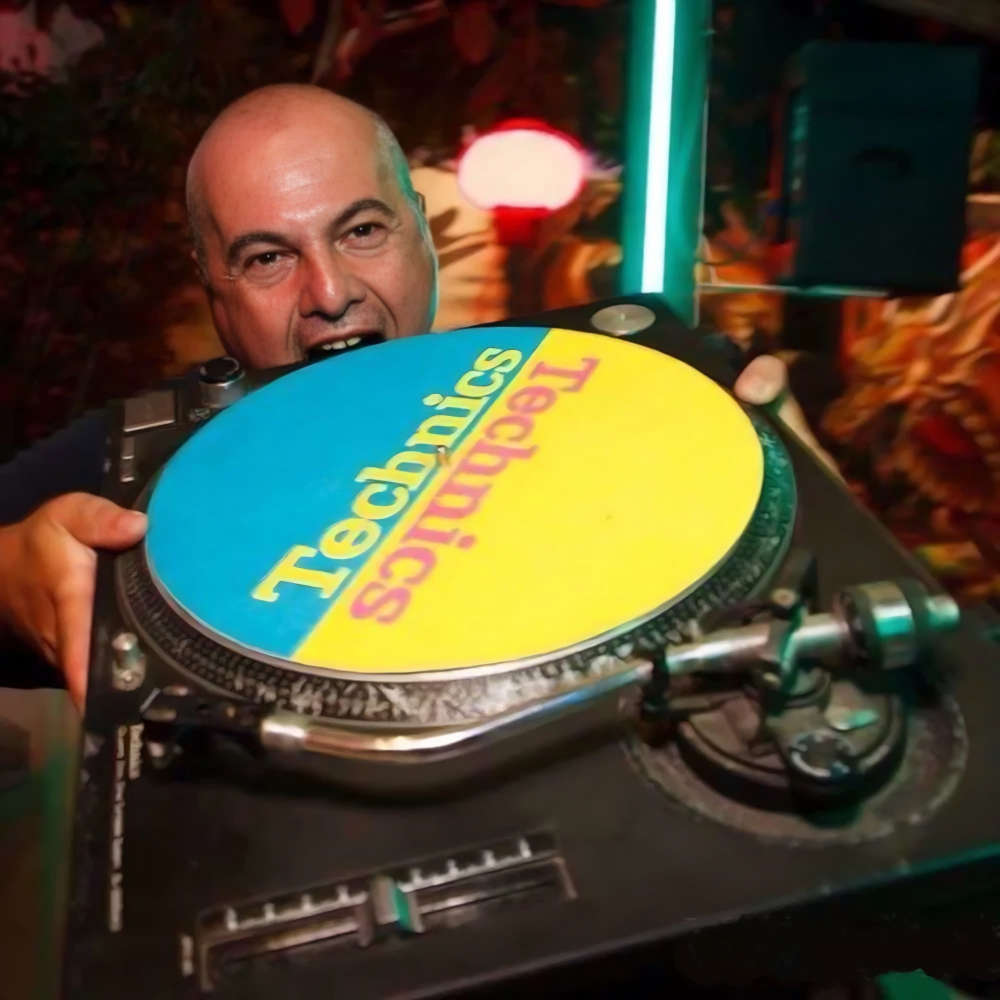 Marco Mei, Italian DJ and producer, playfully biting a Technics turntable slipmat at a club venue.