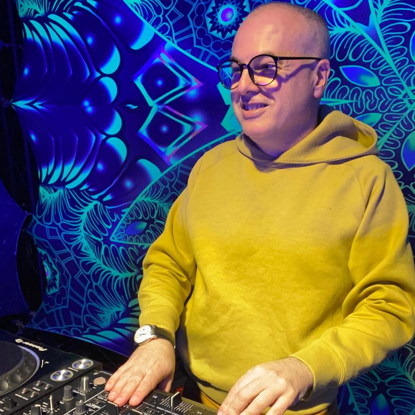 Italian DJ and producer Marco Mei performing at an event ibn Taiwan wearing glasses and a yellow hoodie, colour image.
