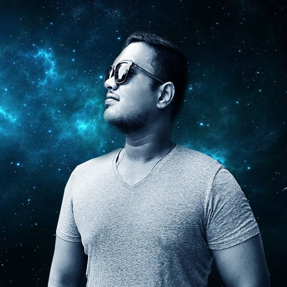 Sri Lankan DJ Rumesh standing with face turned right wearing sunglasses against space background.