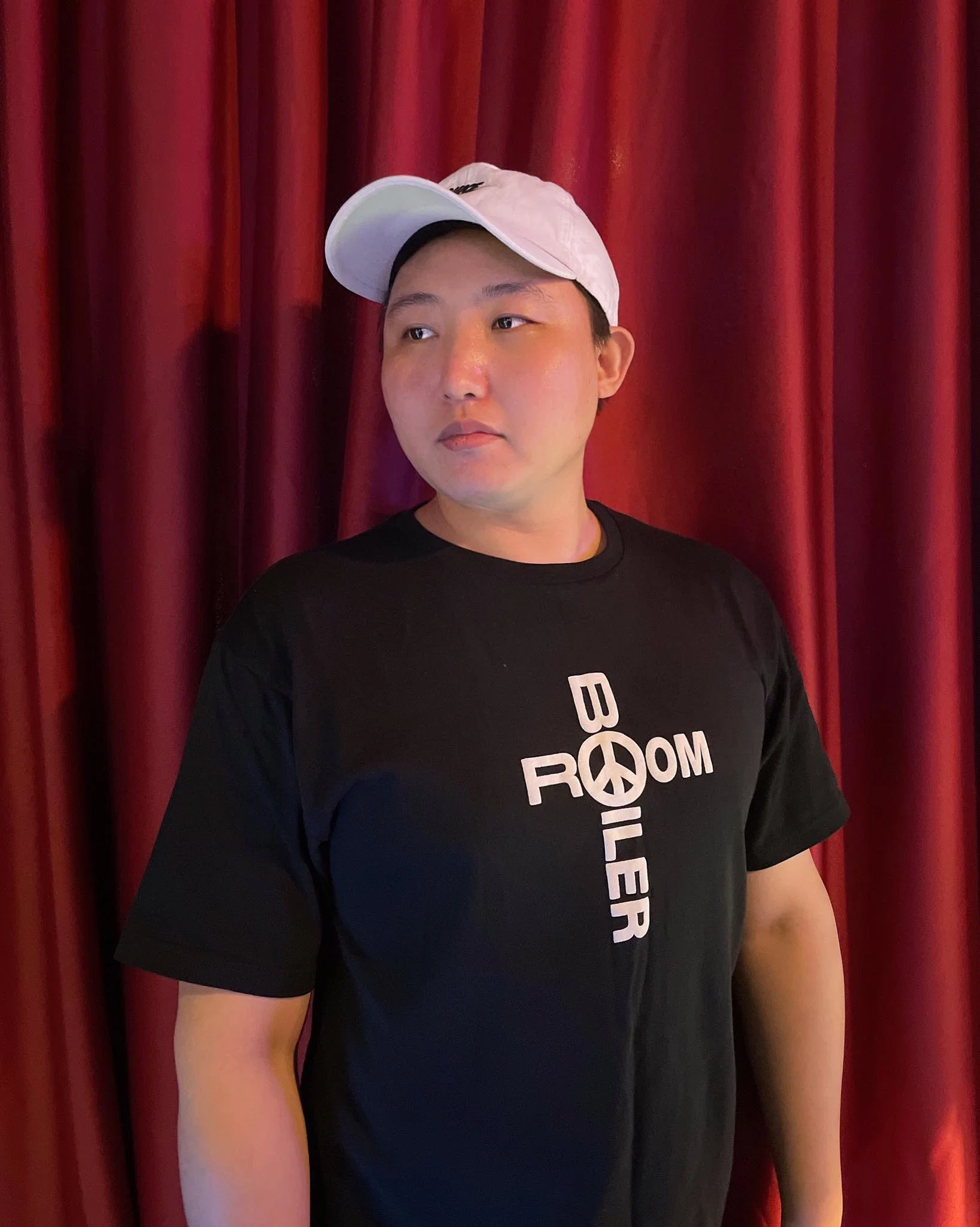 Portrait of South Korean DJ Jenkins standing in front of red curtains, representing his House music sound and role in Seoul’s underground scene.