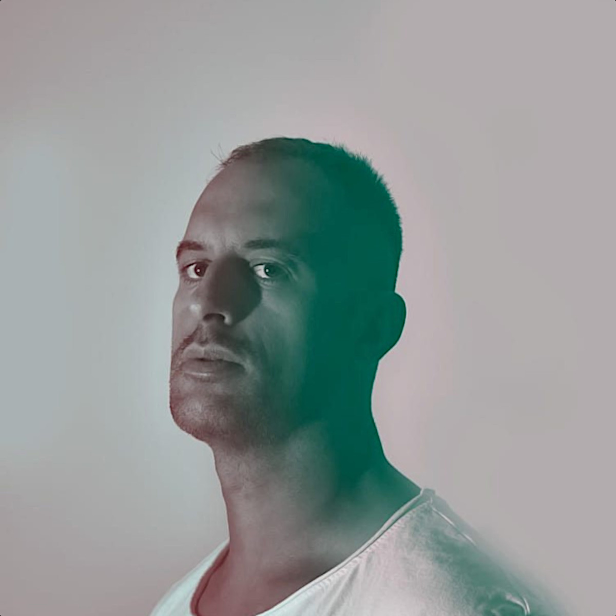 Spanish DJ and producer Benja Molina standing looking at camera over his left shoulder, black and white image with green tinge.