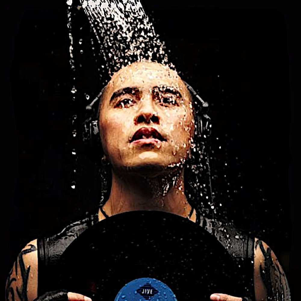 Filipino DJ and producer Tony Pavia standing in a shower wearing headphones and holding a vinyl record in photoshoot, colour image.