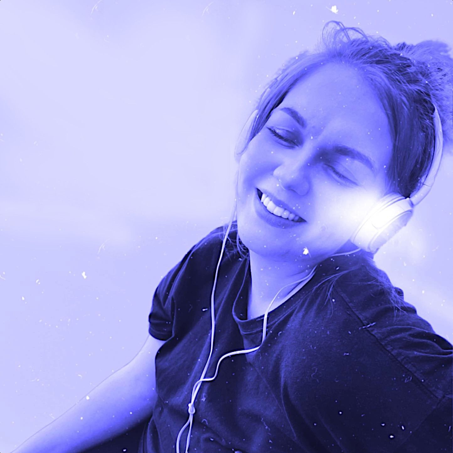 Scottish DJ and radio manager Devious Pink smiling whilst wearing headphones with her eyes closed, black and white image with blue and white hightlighting.