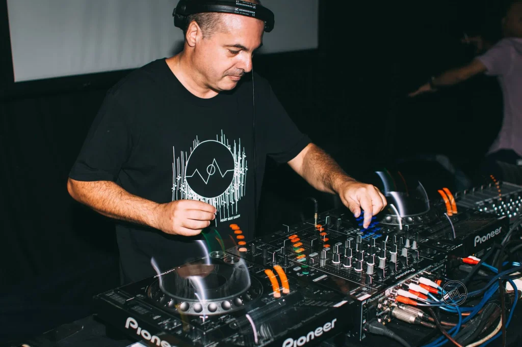Marco Mei, Italian DJ and producer, working the Pioneer CDJs wearing Sennheiser headphones and a Heartbeat Saigon t-shirt.