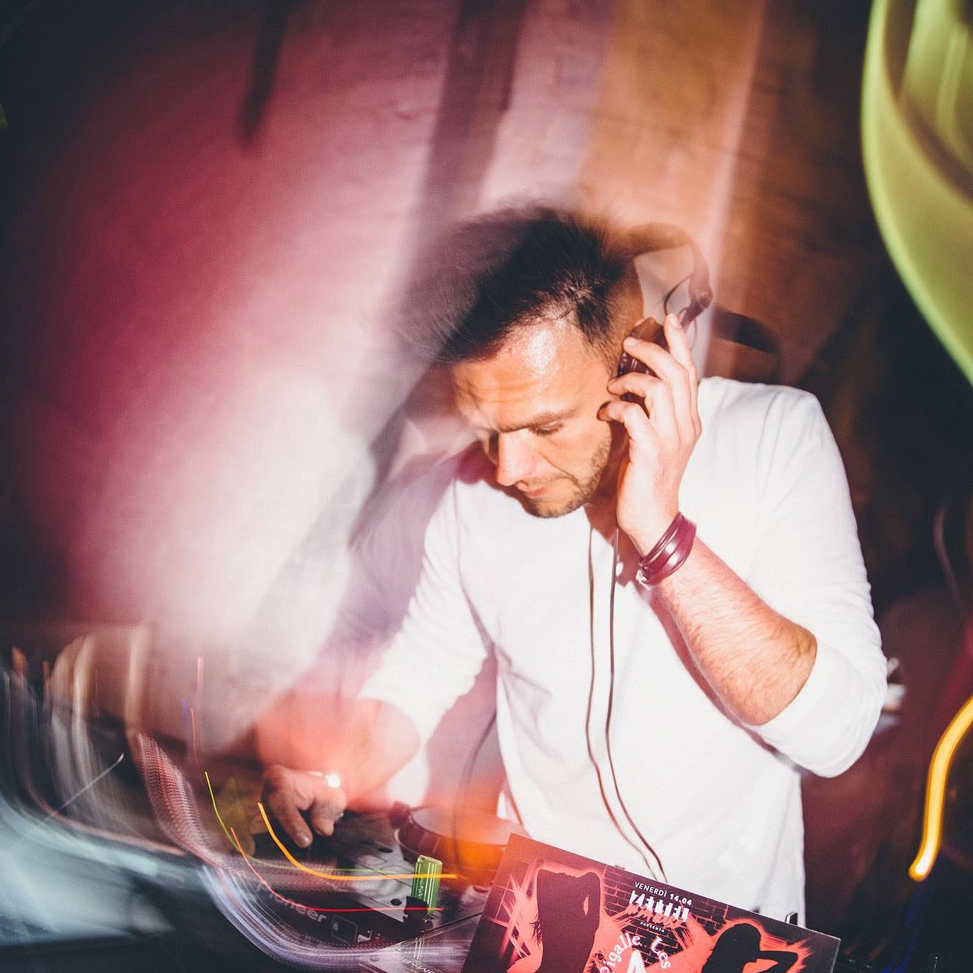 Nhà DJ và nhà sản xuất người Ý Andrea Mirgone biểu diễn tại câu lạc bộ Zettel, hình ảnh màu với hiệu ứng xoáy nhẹ.