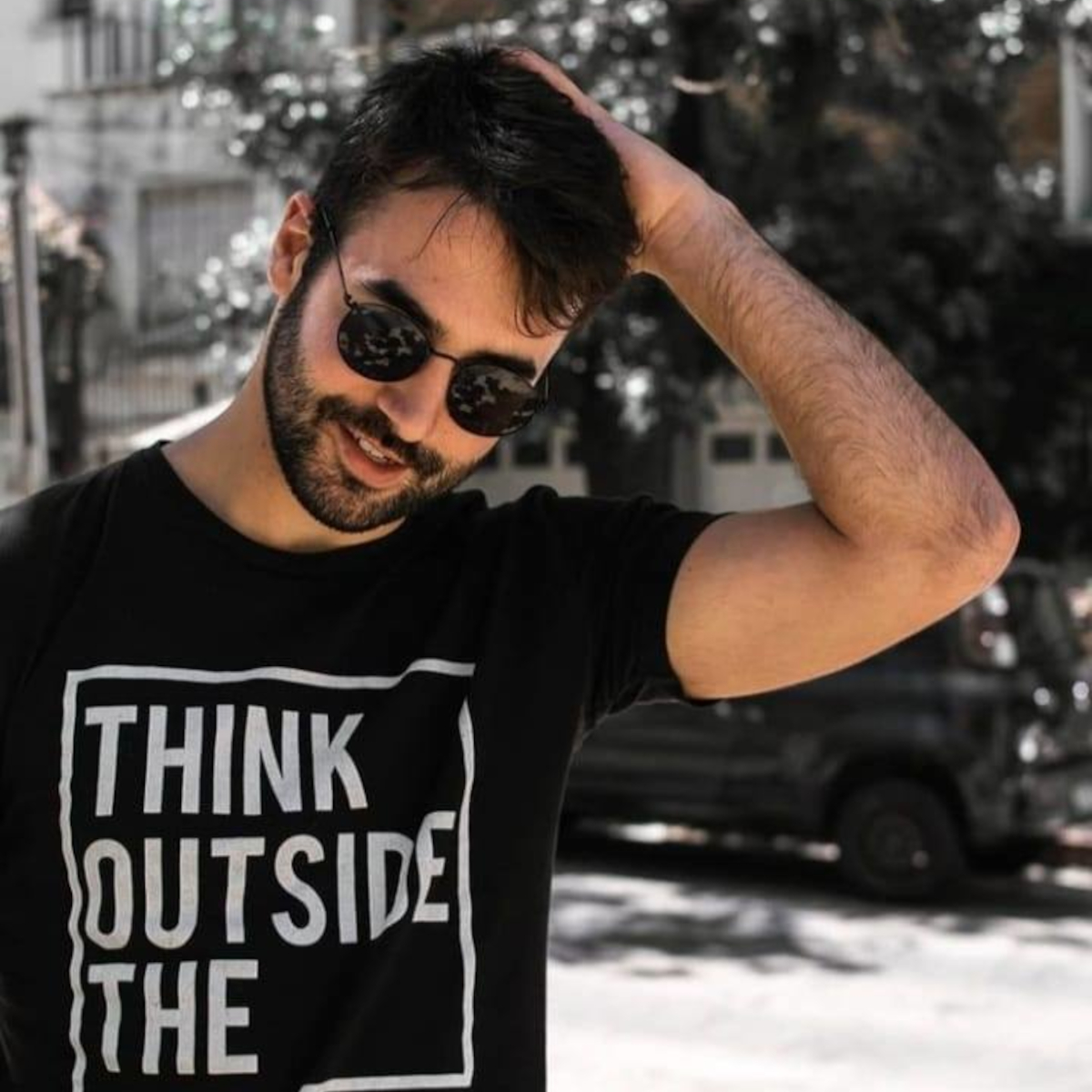 Uraguayan DJ and producer Rodrigo Pochelu standing in street with his left hand on his head and wearing sunglasses, colour image.