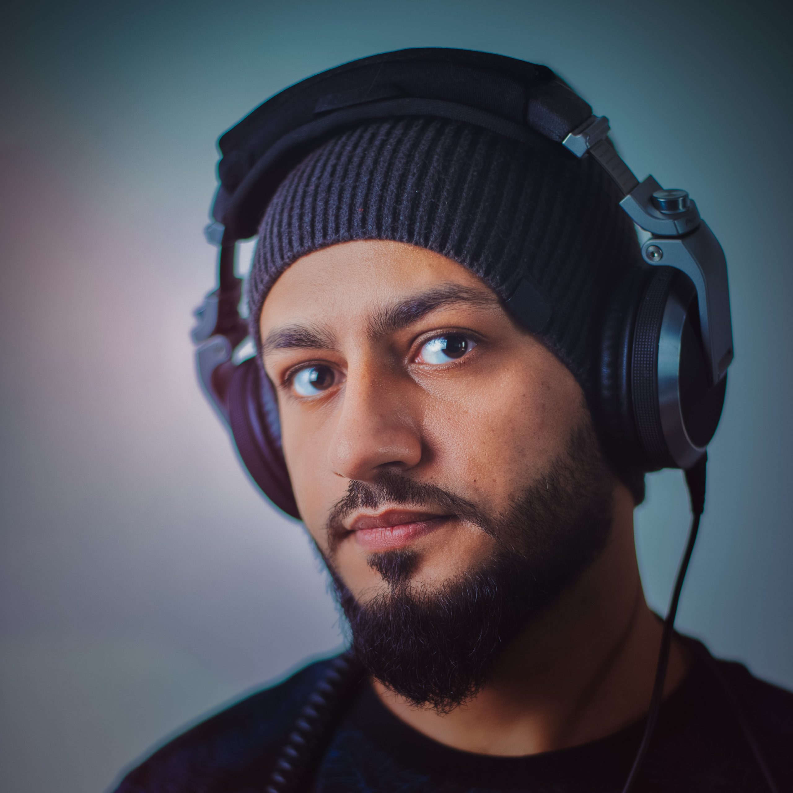 Malaysian based DJ and producer MYDJShadow standing looking at cameraman wearing headphones in profile shot, colour image.