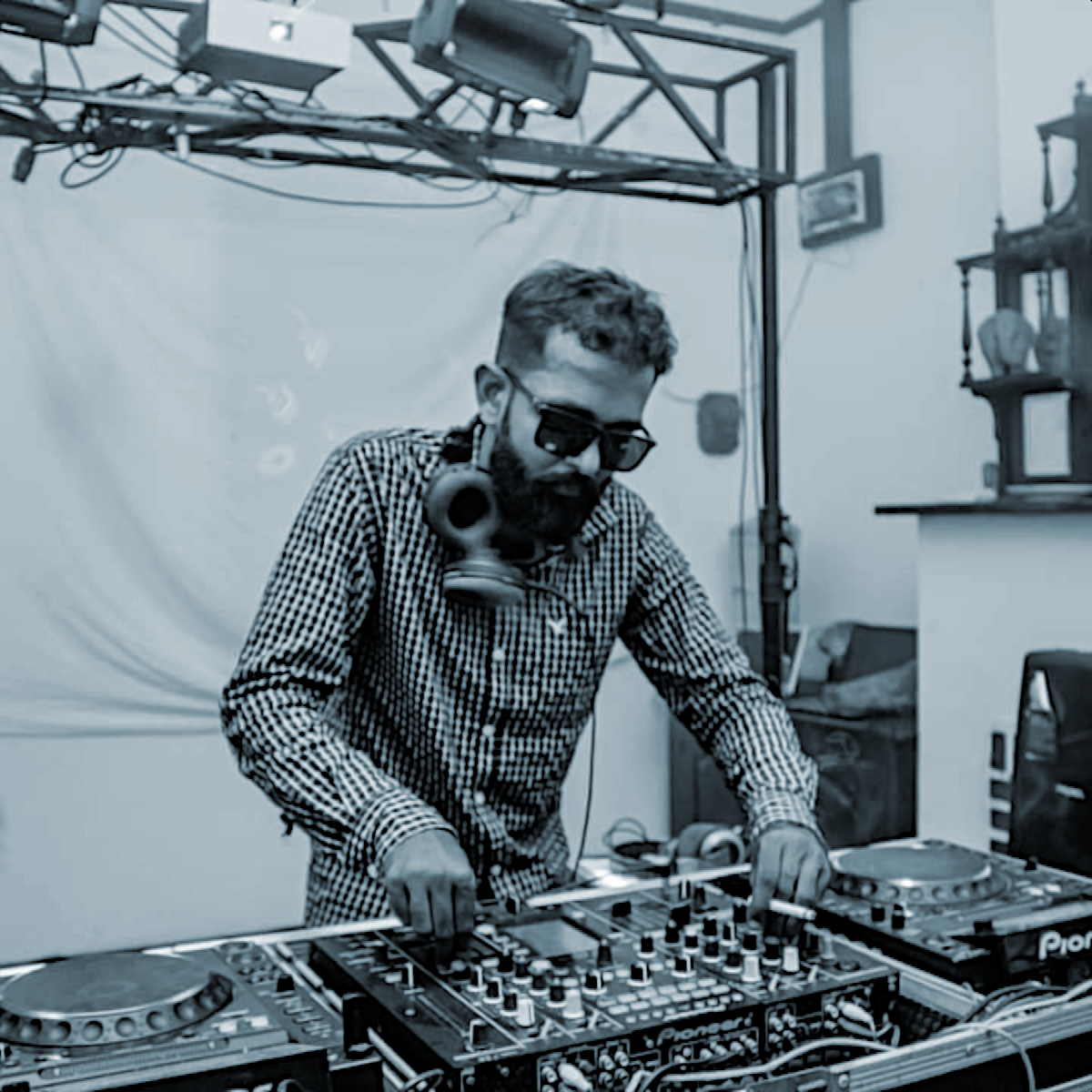 Sri Lankan DJ and producer Noise Generation performing at an event wearing shades, black and white image with blue tinge.