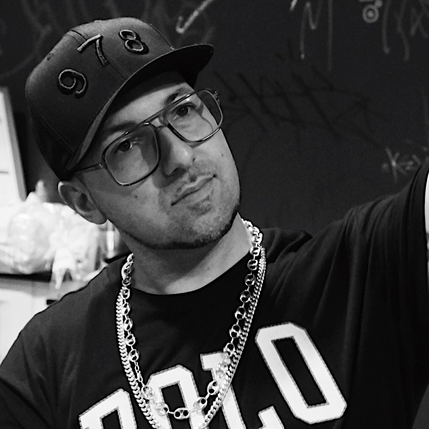 American Rapper and producer Termanology wearing a Polo Shirt, Baseball cap, and glasses, black and White Image.