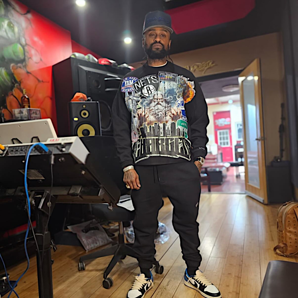 Jamaican producer Rsonist of the Heatmakerz standing in the studio with his production equipment behind him to the right, colour image.
