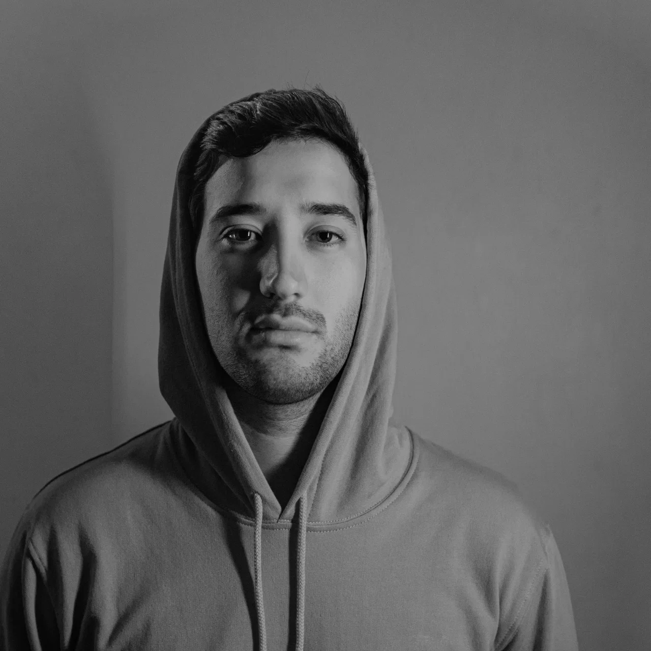 Black-and-white portrait of Peruvian DJ and producer Ni.not wearing a hooded sweatshirt, representing his House, Deep House, Tech House, Minimal and Disco-influenced sound.