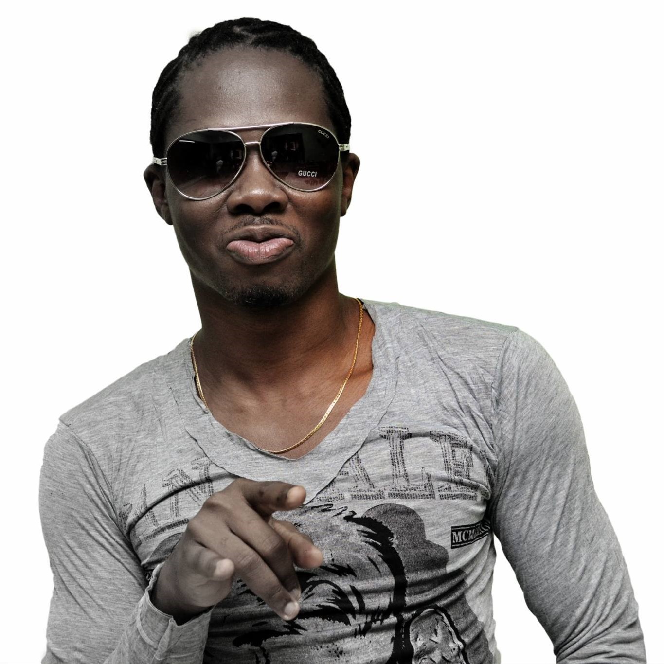 Nigerian DJ Sly Fly standing in an upper body shot pointing at the camera wearing sunglasses, colour image.