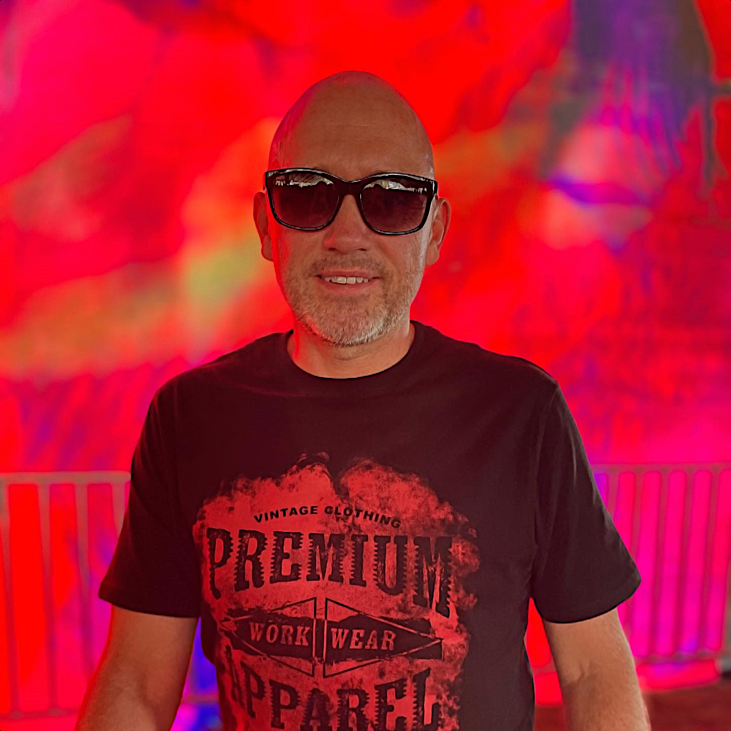 Danish DJ, producer, club owner, and record label owner Tim Andresen standing looking at camera wearing sunglasses in a club with smoke and red lights, colour image.