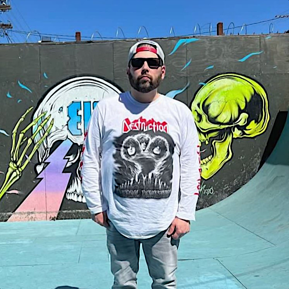 American Rapper and producer GORETEX from NON PHIXION standing in a skatepark wearing baseball cap and sunglasses, colour image.