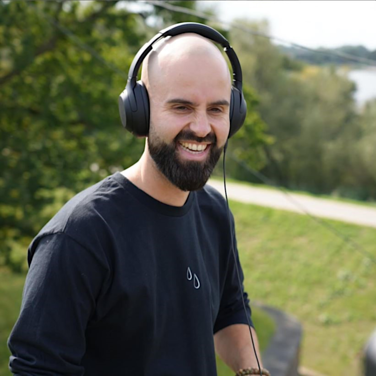 Dutch DJ and producer 4T6 performing at an outdoor event smiling and wearing headphones, colour image.
