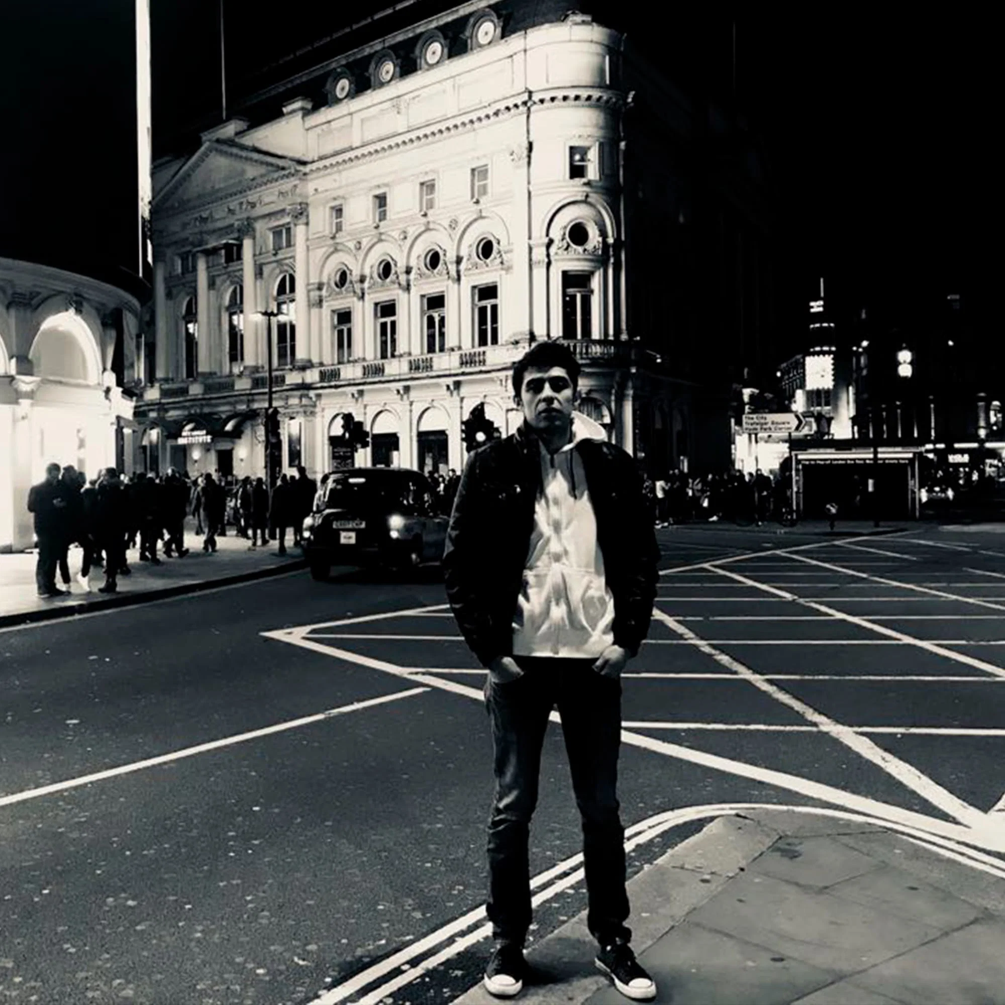 Black-and-white portrait of Mexican DJ and producer Pablo Patch standing on a city street at night with his hands in his pockets, wearing sunglasses, a dark jacket and a light hooded top. His sound draws from Techno, House, Acid Techno, Deep House, Dub Techno and Minimal.