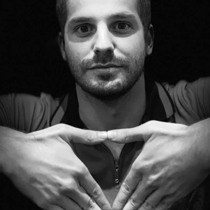 Argentinian DJ and producer Brian Muszkat holding his hands in a triangular shape in front of his chest, black and white image.