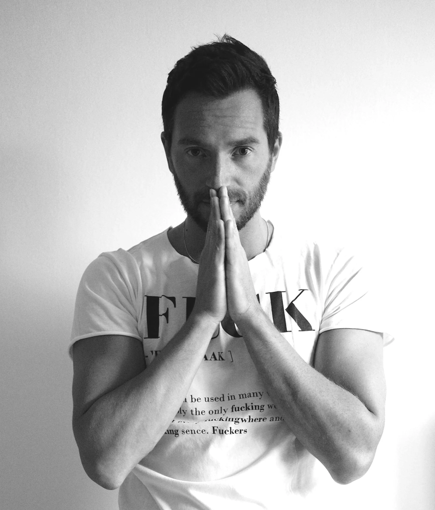 Italian DJ and producer Inve in an upper body shot with him with his hands together in front of him in a prayer stance, black and white image.