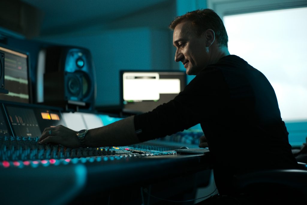 Paul van Dyk adjusting studio equipment inside a professional production studio during promotional photography for VANDIT Next Generation.