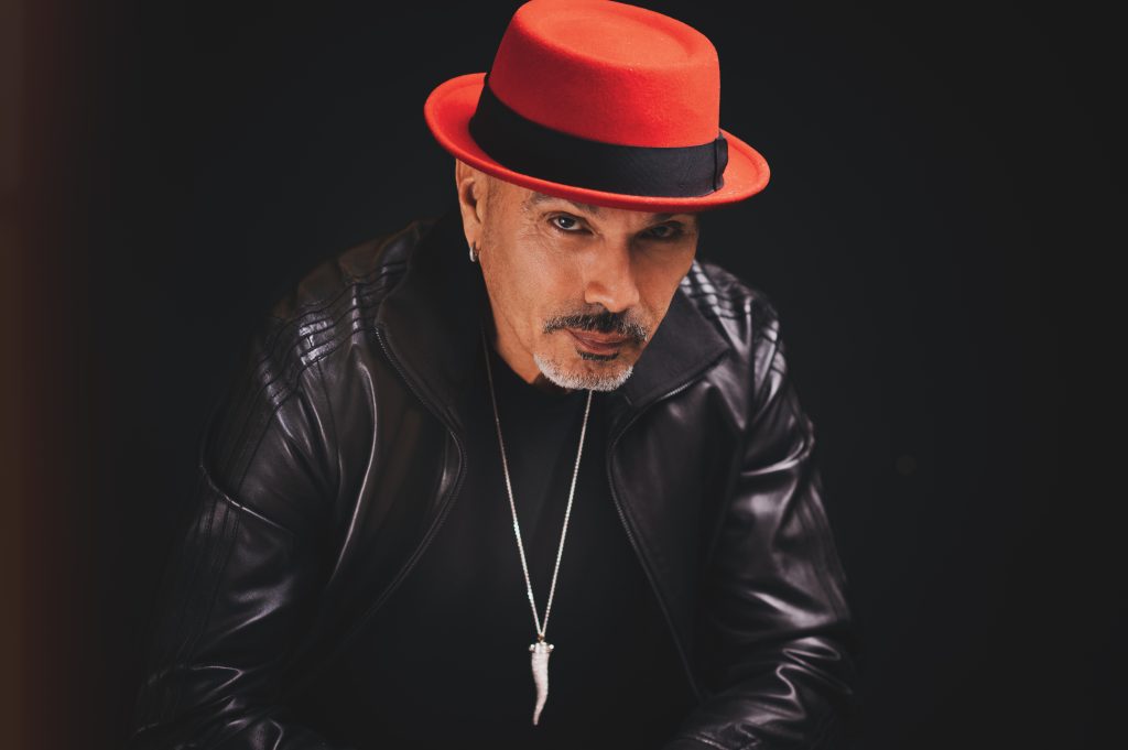 David Morales photographed wearing a red cap and sunglasses during promotional photography for his House single CRAVIN'.