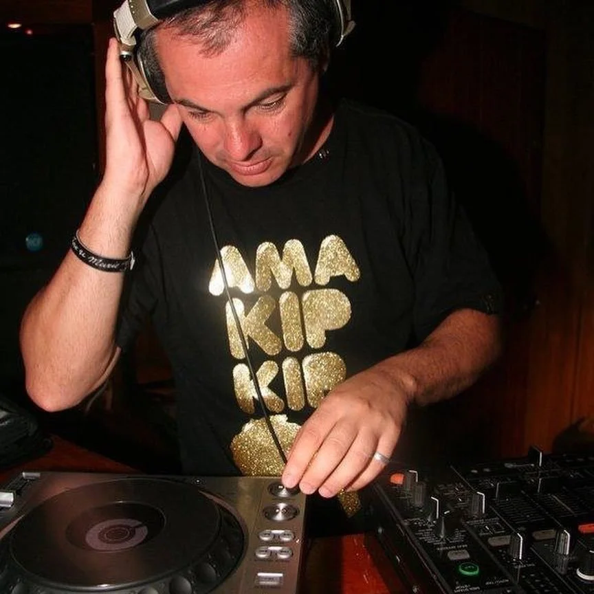 Italian DJ and producer Marco Mei performing as a DJ on Pioneer CDJs with one hand on headphones and one on CDJ, colour image