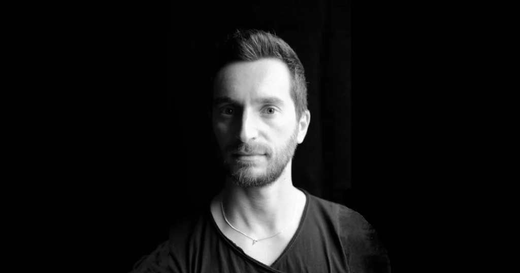 Italian DJ and producer INVE standing in upper body shot looking at camera with black background and shadows, image in Black and White.