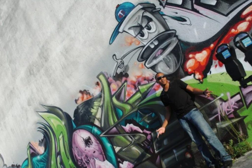 American DJ and producer Gerard leaning against a Graffiti wall in Florida, U.S.A with his arms outstretched, colour image.