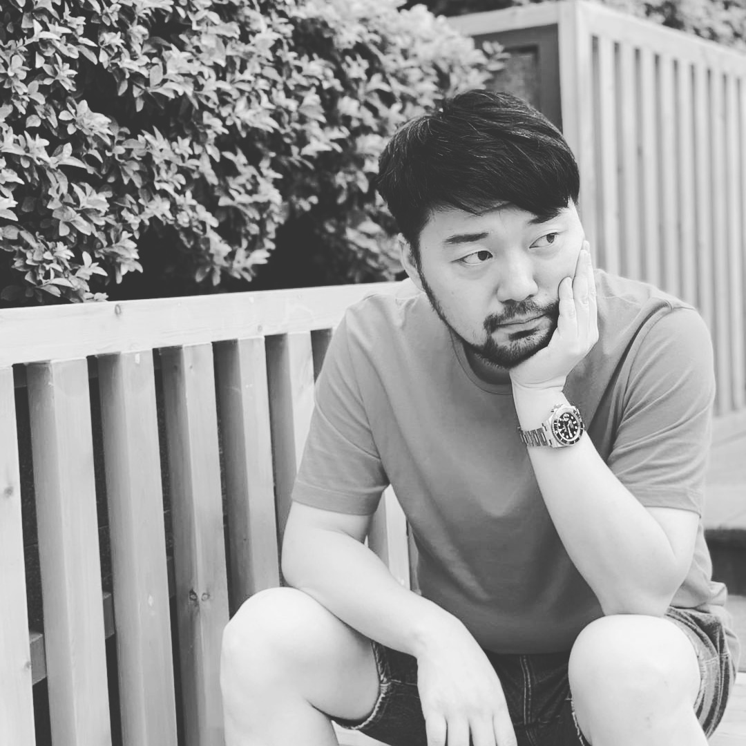 Chinese DJ and producer Hu Yang sitting holding his face with his left hand, black and white image.