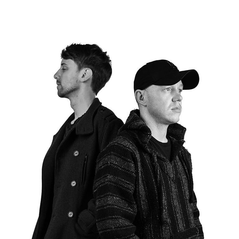 Luc Angenehm and Deep Suite (Gary Pilz) (LADS) staning back to back facing left and right in black and white image.