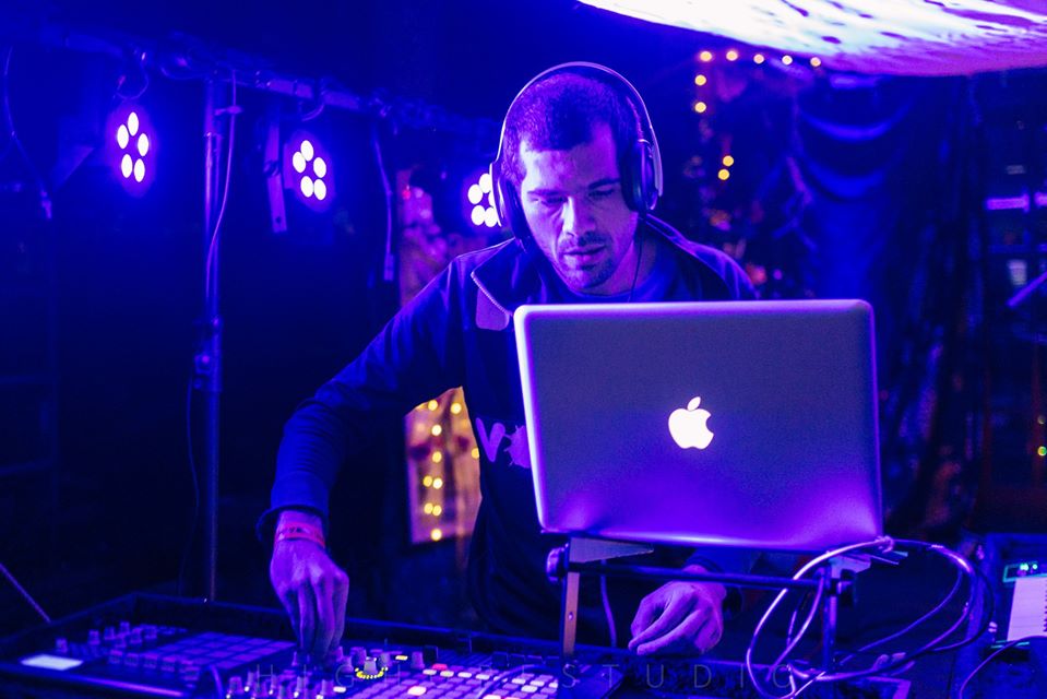 Romanian DJ Bipolar Bear performing as a DJ at an event wearing headphones and looking at laptop, colour image